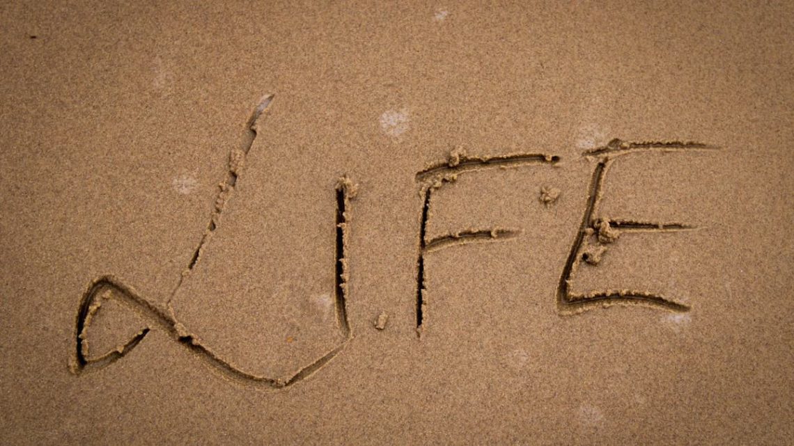 The word 'Life' artistically drawn in sand, symbolizing change and nature's impermanence.