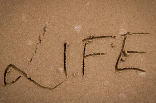 The word 'Life' artistically drawn in sand, symbolizing change and nature's impermanence.